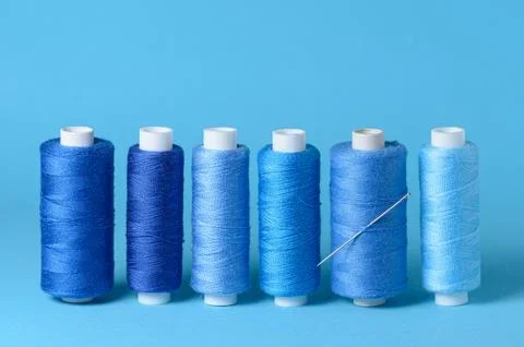 Row of blue thread spools with needle Stock Photos