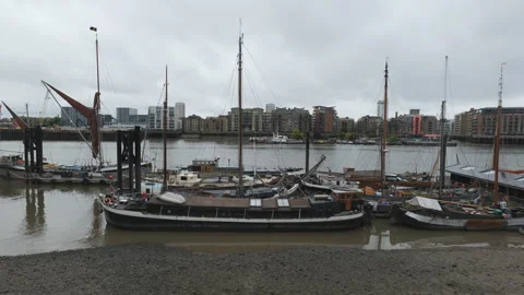 A row of boats docked on the river with modern residential buildings. Stock Footage 279936480