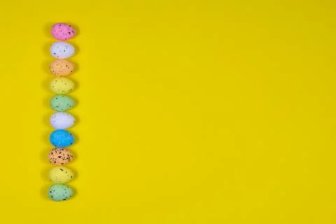 A row of bright Easter eggs on a yellow background. Place for an inscription 库存照片