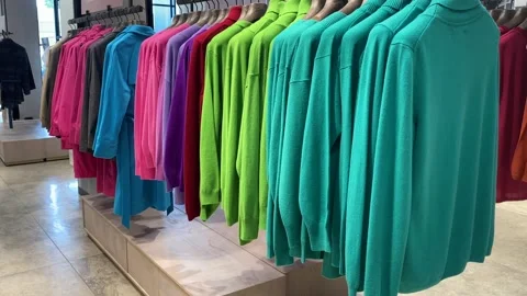 Row of brightly colored sweaters and outerwear items organized on hangers i.. Stock Footage 314124500