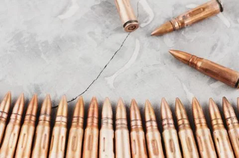 Row of bullets and three bullets on grey broken concrete Stock Photos
