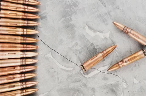 Row of bullets and three bullets on grey broken concrete Stock Photos
