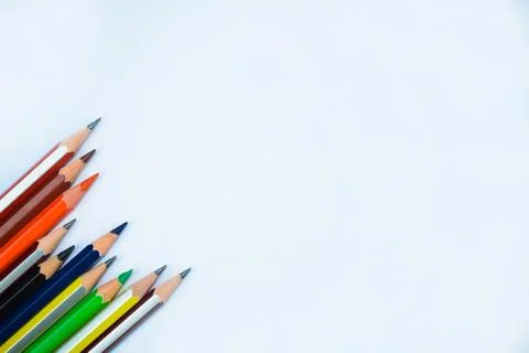 A row of bunch of different colored wood pencil crayons on a white background Foto stock