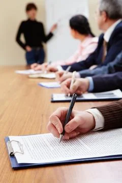 Row of business people making notes during presentation Stock Photos