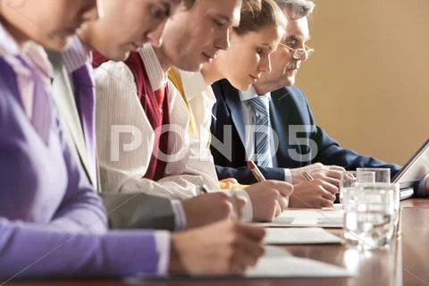 Row of businesspeople writing review of their work with senior boss at backgroun Stock Photos