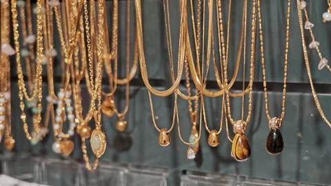 Row of chains with pendants and small stones in jewelry store, concept of Stock Footage 330752131