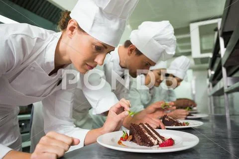 Row Of Chefs Garnishing Dessert