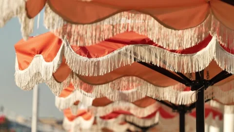 Row of classic orange fringed beach umbrellas providing shade on a sunny day Stock Footage 344697748