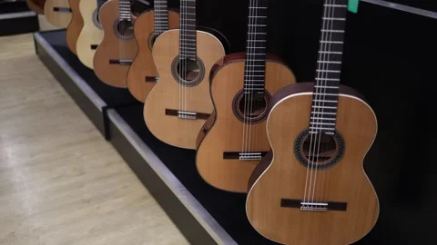 A row of classical acoustic guitars with warm wooden tones and intricate rosette Stock Footage 294706662