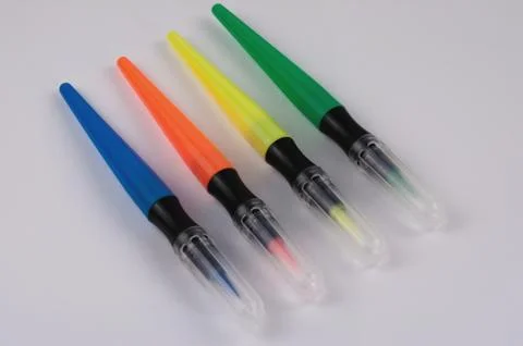 Row of colored marker brushes with transparent plastic tip on white table Foto stock