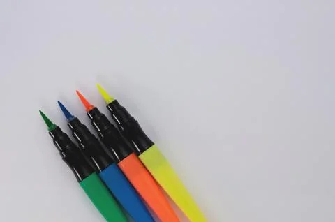 Row of colored markers brushes on white school desk with copy space Stock Photos