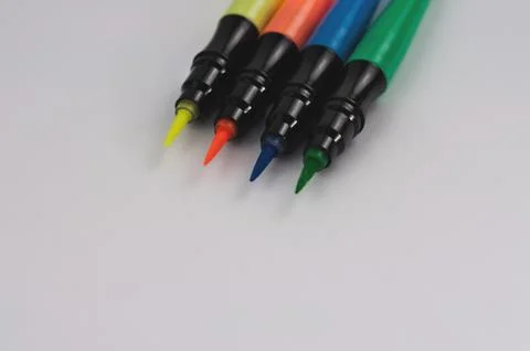 Row of colored markers brushes on white school desk or office table with copy Stock Photos
