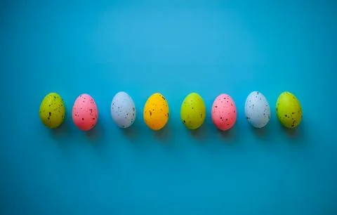 Row of Colorful Easter Eggs on Blue Background with Copy Space Stock-Fotos