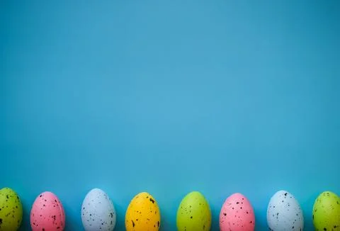 Row of Colorful Easter Eggs on Blue Background with Copy Space Stock Photos