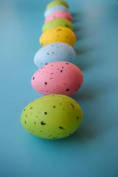 Row of Colorful Easter Eggs on Blue Background with Copy Space Stock Photos