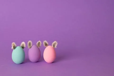 Row of colorful Easter eggs with willow bud ears painted in simple colors on  Фото