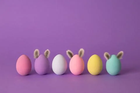 Row of colorful Easter eggs with willow bud ears painted in simple colors on  Фото