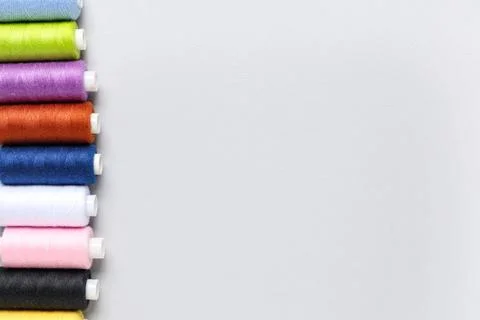 Row of colorful thread spools on grey background 写真素材