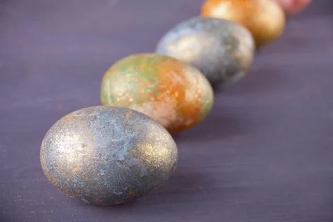 Row of colorfully painted nacreous Easter eggs on black wooden background Stock Photos