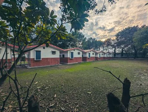 Row of cottages in a grassy park at sunset Stock Photos