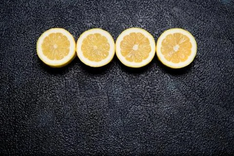 Row of cut lemons on dark background with space for text Stock Photos
