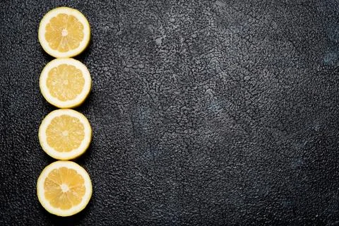 Row of cut lemons on dark background with space for your text Stock Photos