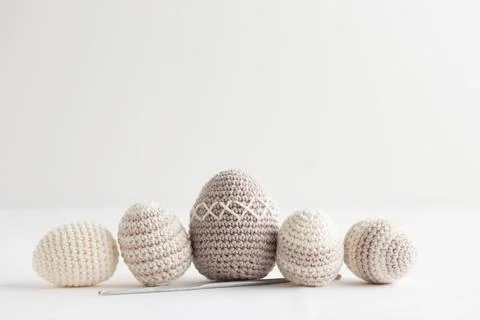 Row of cute striped pattern crocheted eggs, pastel color on a white Stock Photos