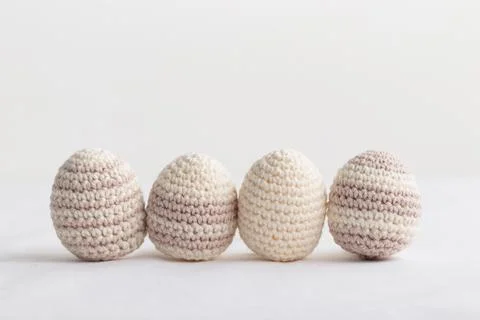 Row of cute striped pattern crocheted eggs, pastel color on a white Fotos de archivo
