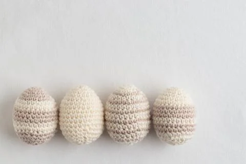 Row of cute striped pattern crocheted eggs, pastel color on a white Foto stock