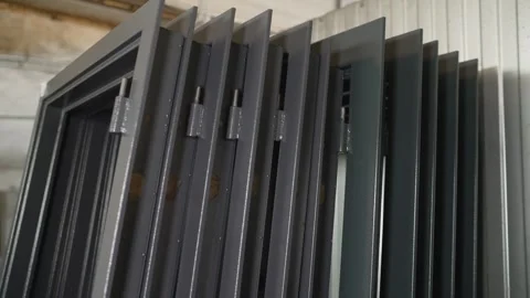 Row of dark grey metal door frames with hinges and paper labels standing in Stock Footage 346750002