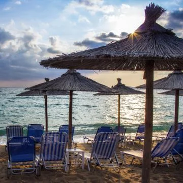 Row deckchairs on beach at sunset Stock Photos
