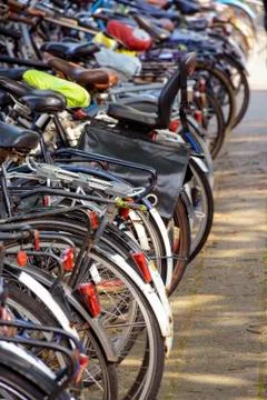 A row different bicycles parked outside in the parking lot. Stock Photos