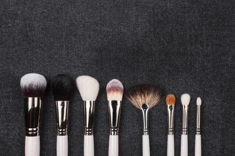 Row of different makeup brushes in white covering Stock Photos