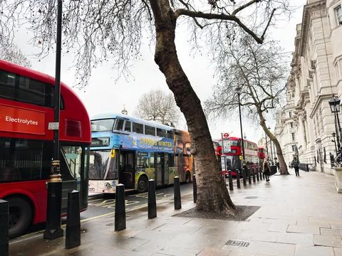 Row of double decker buses and pedestrians on a London, UK street with wint.. Foto stock