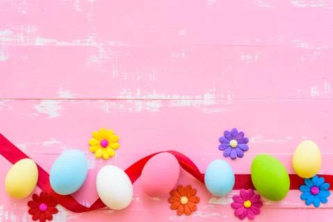 Row Easter eggs with colorful paper flowers on bright pink and white wooden b Stock Photos