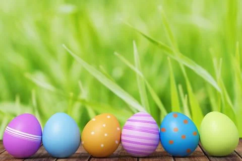 Row of Easter eggs on grass with a wood background Stock Photos