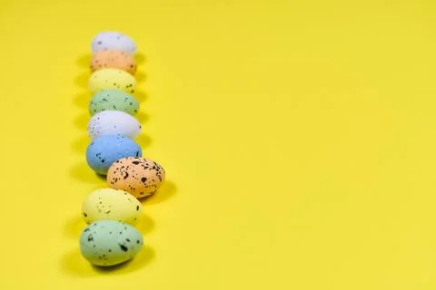A row of Easter eggs on a yellow background. Easter concept. View from above Stock Photos