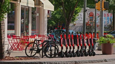 A Row of Electric E-Scooters Sit on the Corner of a Street in Neighborhood Stock Footage 130866728