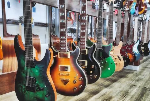 A row of electric solid-body guitars hanging on a display rack in a music sho Stock Photos