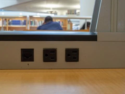 Row of electrical plug outlets in a library with man in background Stock Photos