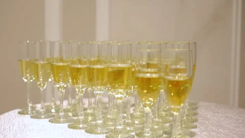 A row of elegant champagne flutes filled with sparkling wine displayed on a Video stock 324243666