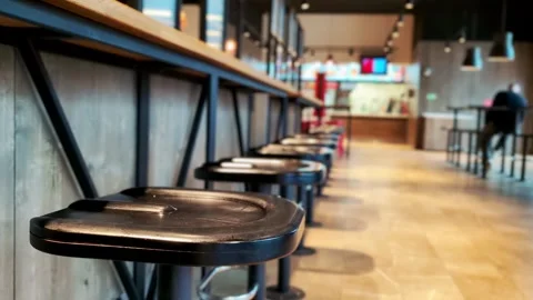 Row empty black bar stools at wooden counter in modern fast food restaurant Stock Footage 344094494