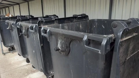 Row of empty black industrial dumpsters with wheels lined up  Vídeo Stock 339096797