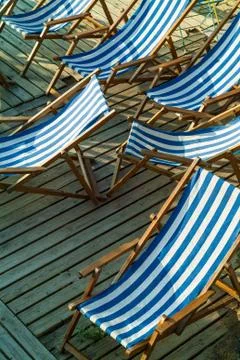 Row of empty blue and white striped beach chairs Stock Photos