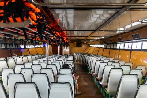 Row of empty chairs inside a ferry. Orange Life jackets in th eover-head comp Stock Photos