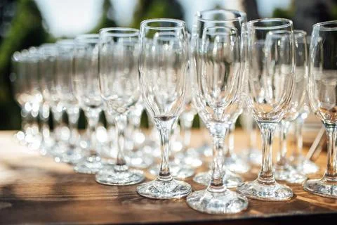 Row of empty champagne glasses on a table outdoors with sun reflection Stock Photos