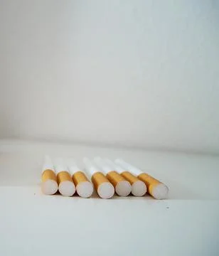 A row of empty cigarette filter tubes with yellow filters neatly arranged Фото