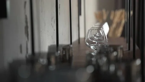 Row of empty cognac glasses stand on dark shelving unit in beautiful interior. Stock Footage 236582346