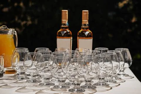 Row of empty cognac snifter glasses arranged on a white table with two bottle Stock Photos
