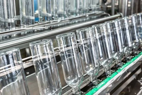 Row of empty glass bottles on automatic conveyor at plant Stock Photos